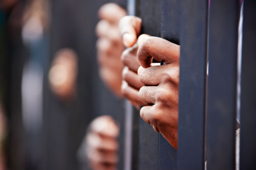 Hands grab prison bars.